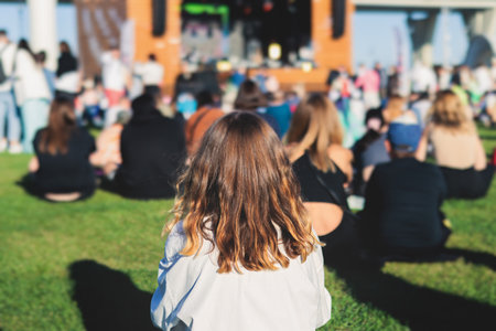 Crowded open air festival concert with scene lights with musicians band on stage at the venue, rock show performance, with concert-goers attendees, audience on dance floor during summer festivalの写真素材