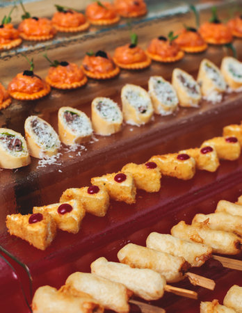 Catering table, beautifully decorated banquet with variety of with different food snacks appetizers on corporate birthday party event or wedding celebration, canape, salad, delicatessen settingの写真素材