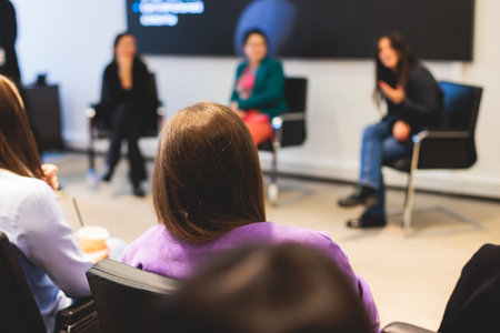 Female participants audience at the symposium meeting, attendees in conference room hall listens to lecturer, group of women on a congress together listen to speaker on a stage at master-classの写真素材