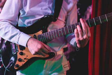 Concert view of an electric guitar player with vocalist and rock band performing in a club, male musician guitarist on stage with audience in a crowded concert hall arenaの写真素材
