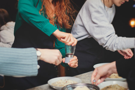 Group of people in a cooking class studio, adults preparing different dishes in the kitchen together, people in aprons learn on culinary master class, chef uniform, hands in gloves, Italian cuisineの写真素材