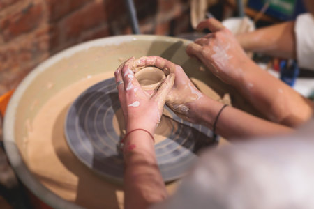 Pottery lesson master class for kids children, process of making clay pot on pottery wheel, potter hands creating ceramic crockery handcrafts, ceramist molding and painting jar or vaseの写真素材