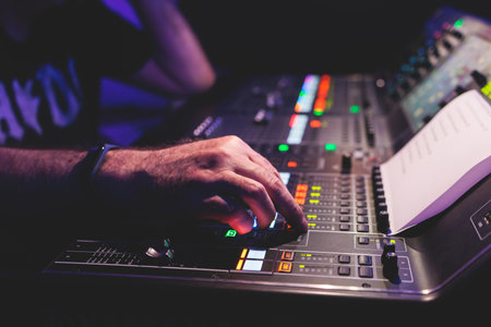 View of lighting engineer operator working on mixing console workplace during live event concert on...