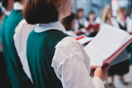 Church choir concert in cathedral, choral artists singing, group of European boys and girls singing in a chorus, students and choristers in white and green uniform performing on stage with conductorの写真素材
