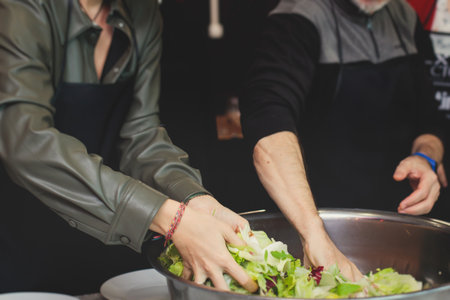 Group of people in a cooking class studio, adults preparing different dishes in the kitchen...