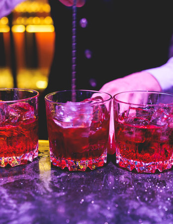 Bartender working, beautiful row line of different colored liquor alcohol cocktails on a party in a bar, and others on catering banquet on event, barman mixing drinks and beverages in a clubの写真素材