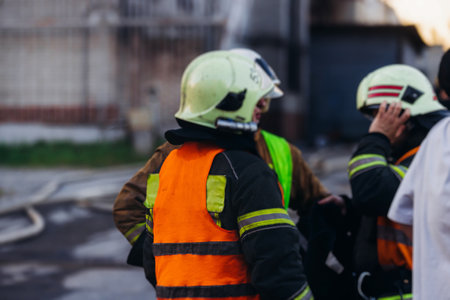 Group of fire men in uniform during fire fighting operation in the city streets, firefighters with...