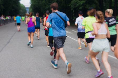 Marathon runners crowd, sportsmen participants start running the half-marathon in the city streets, crowd of sportswomen joggers in motion, group athletes outdoor training competition in summer dayの写真素材