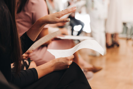 Choir rehearsal, vocal class singing in the auditorium hall, group of students on stage holding white sheets and singing, orchestra vocals class in music school with a teacher, adults sing in chorusの写真素材