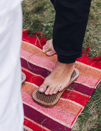 Standing on sadhu board, process of barefoot standing on nails therapy, view of legs feet on nails, yoga and sadhu practice, outdoor meditation with nailing practice, a wooden nail board, summer dayの写真素材