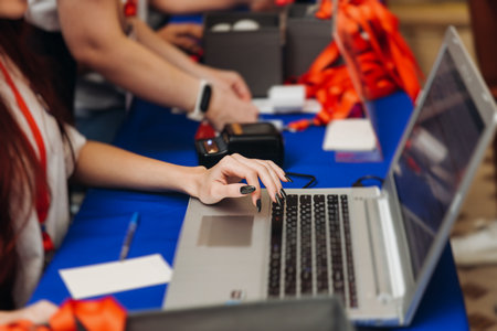 Process of checking in on conference congress forum event, registration desk table, visitors and attendees receiving lanyard with name badge and entry wristband bracelet and register electronic ticketの写真素材