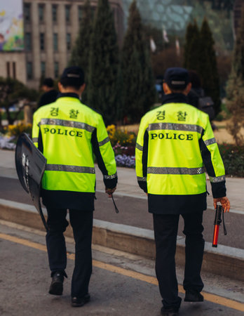 Korean police squad formation in protective uniform with "Police" logo, policemen patrol maintain public during political demonstration protest rally in the streets of Seoul city center, South Koreaの写真素材