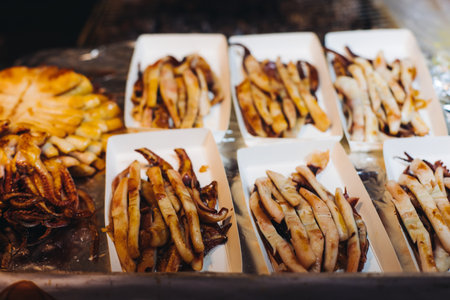 Korean Spicy Grilled Squid, Ojingeo tonggui, variety of different street food selection in Seoul, South Korea, night market with local vendor stalls cooking tasty dishesの写真素材