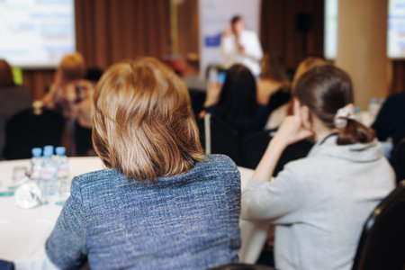 Female audience at the symposium meeting, participants in conference room hall listens to lecturer, group of women on a medical congress together listen to speaker on a stage at master-classの写真素材