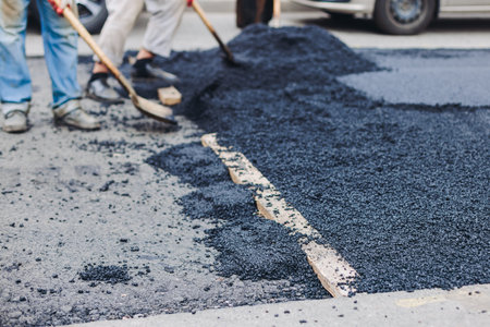 Roadworks, process of asphalting, blacktopping and paving new road layer, laying new asphalt road pavement, paver machine and steam roller compactor, city street construction site, vehicle workingの写真素材