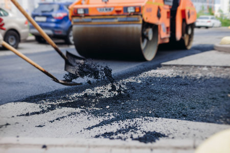 Roadworks, process of asphalting, blacktopping and paving new road layer, laying new asphalt road pavement, paver machine and steam roller compactor, city street construction site, vehicle workingの写真素材