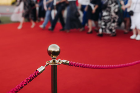 Red carpet with ropes and golden barriers on a luxury party entrance, cinema premiere film festival event award gala ceremony, wealthy rich guests arriving, outdoor decoration elements, summer dayの写真素材