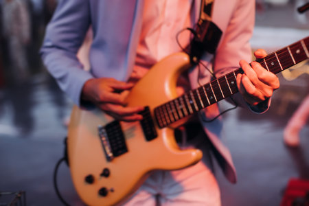 Concert view of an electric guitar player with vocalist and rock band performing in a club, male...