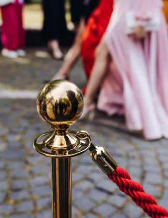 Red carpet with ropes and golden barriers on a luxury party entrance, cinema premiere film festival event award gala ceremony, wealthy rich guests arriving, outdoor decoration elements, summer dayの写真素材