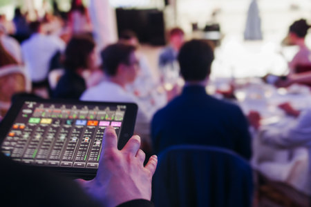 View of lighting technician with tablet, operator controlling sound and light during live event concert on stage show broadcast, technician with professional equipment, working on mixing consoleの写真素材