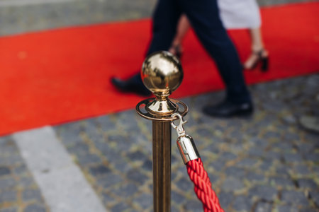 Red carpet with ropes and golden barriers on a luxury party entrance, cinema premiere film festival event award gala ceremony, wealthy rich guests arriving, outdoor decoration elements, summer dayの写真素材