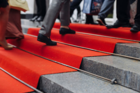 Red carpet with ropes and golden barriers on a luxury party entrance, cinema premiere film festival event award gala ceremony, wealthy rich guests arriving, outdoor decoration elements, summer dayの写真素材