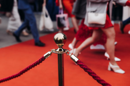Red carpet with ropes and golden barriers on a luxury party entrance, cinema premiere film festival event award gala ceremony, wealthy rich guests arriving, outdoor decoration elements, summer dayの写真素材