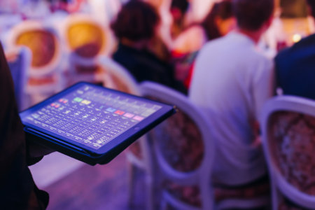 View of lighting technician with tablet, operator controlling sound and light during live event...