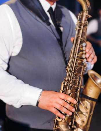 Concert view of saxophonist musician, saxophone sax player with vocalist and musical band during jazz orchestra show performing music on a stage in the scene lights, concert in a musical club hallの写真素材
