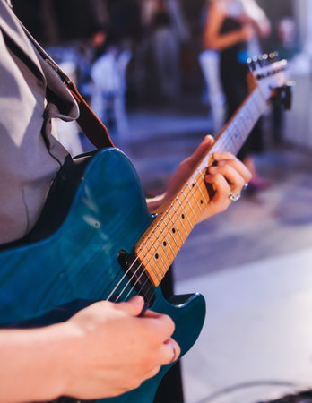 Concert view of an electric guitar player with vocalist and rock band performing in a club, male musician guitarist on stage with audience in a crowded concert show club hall arena, hands on guitarの写真素材