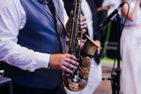 Concert view of saxophonist musician, saxophone sax player with vocalist and musical band during jazz orchestra show performing music on a stage in the scene lights, concert in a musical club hallの写真素材