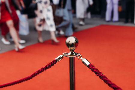 Red carpet with ropes and golden barriers on a luxury party entrance, cinema premiere film festival event award gala ceremony, wealthy rich guests arriving, outdoor decoration elements, summer dayの写真素材