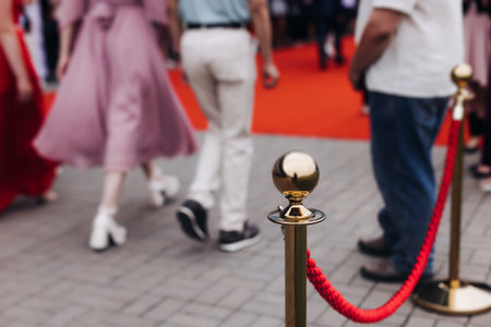 Red carpet with ropes and golden barriers on a luxury party entrance, cinema premiere film festival event award gala ceremony, wealthy rich guests arriving, outdoor decoration elements, summer dayの写真素材