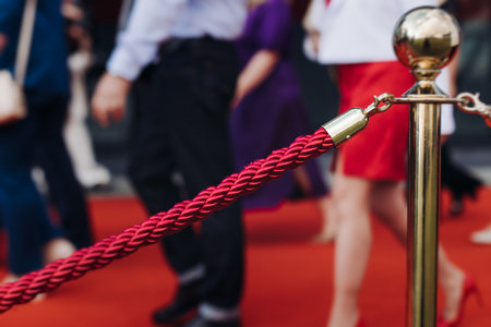 Red carpet with ropes and golden barriers on a luxury party entrance, cinema premiere film festival event award gala ceremony, wealthy rich guests arriving, outdoor decoration elements, summer dayの写真素材