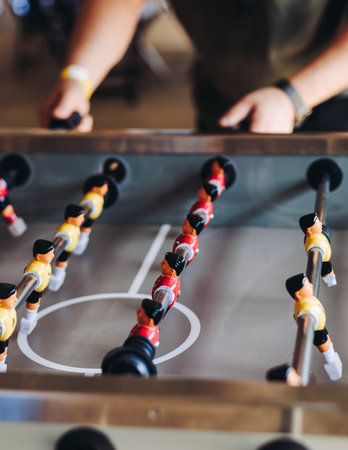 Group of friends playing kicker in a sports bar room, colleagues playing table football, table soccer game in the office, having fun, tabletop football match competition at work, backyard gamesの写真素材