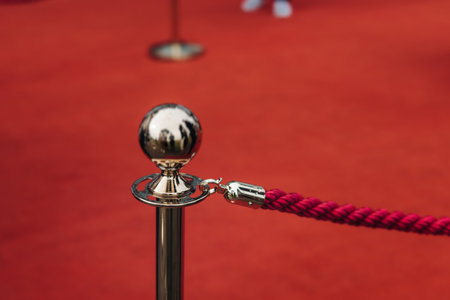 Red carpet with ropes and golden barriers on a luxury party entrance, cinema premiere film festival event award gala ceremony, wealthy rich guests arriving, outdoor decoration elements, summer dayの写真素材