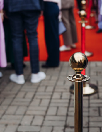 Red carpet with ropes and golden barriers on a luxury party entrance, cinema premiere film festival event award gala ceremony, wealthy rich guests arriving, outdoor decoration elements, summer dayの写真素材