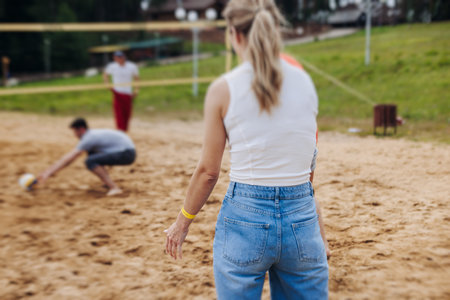 Beach volleyball game, team of adult friends athletes play volleyball by the sea, players on the outdoor playground with net, white sand court field, sports team during the game, in a summer sunny dayの写真素材