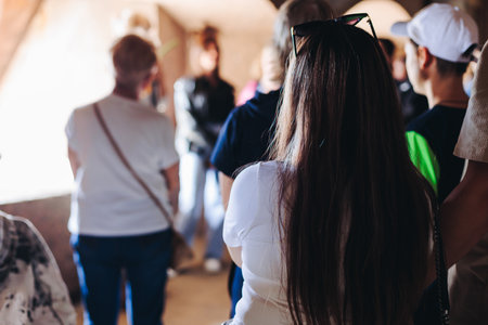 Group of students and tourists in a science museum exhibition, excursion tour with guide, a docent with a tourist visitors, school field trip, adult attendees of technical museum exposition galleryの写真素材