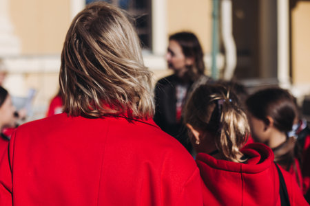 Group of school pupils and students on outdoor excursion tour in the city streets with guide, a docent with a tourist young visitors wearing red, school field trip, urban tour in the summer sunny dayの写真素材