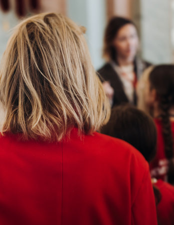 Group of kids children on excursion in a museum gallery, school pupils and students tour with guide, a docent with a tourists, young visitors wearing red, school field trip, art exhibitionの写真素材