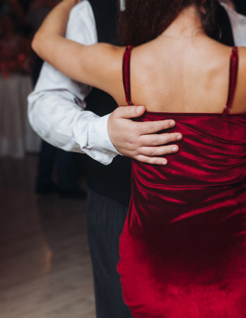 Couples dancing traditional latin argentinian dance milonga in a ballroom, tango salsa bachata lesson in red and purple lights, performance rehearsal, evening dance school class festivalの写真素材