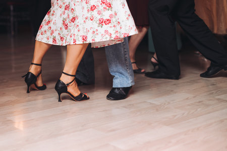 Dancing stiletto shoes of couples dancing traditional latin argentinian dance milonga in the ballroom, tango salsa bachata lesson in red and purple lights, evening dance school class festivalの写真素材