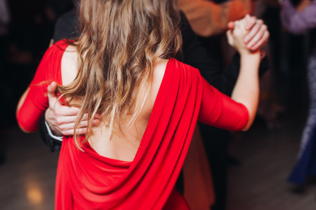 Couples dancing traditional latin argentinian dance milonga in a ballroom, tango salsa bachata kizomba lesson in red and purple lights, performance rehearsal, evening dance school class festivalの写真素材