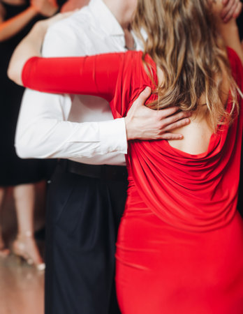 Couples dancing traditional latin argentinian dance milonga in a ballroom, tango salsa bachata lesson in red and purple lights, performance rehearsal, evening dance school class festivalの写真素材