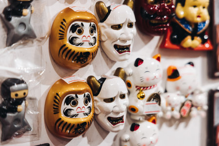 Traditional Japanese tourist souvenirs and gifts from Kyoto, Kansai, Japan, with daruma figures, kitsune fox, tengu mask, refrigerator magnets, toys figurines, key ring keychain, in a local vendor gift shopの写真素材
