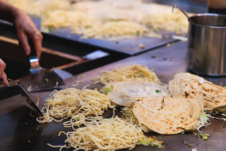 Okonomiyaki Hiroshima-Style - popular Japanese Street Food, pancake with yakisoba noodles, fried...