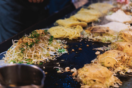 Okonomiyaki Hiroshima-Style - popular Japanese Street Food, pancake with yakisoba noodles, fried...