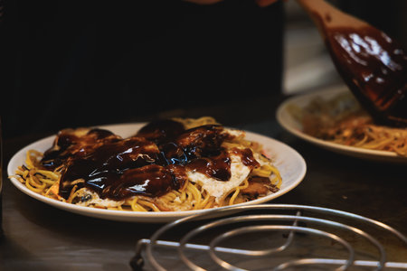 Okonomiyaki Hiroshima-Style - popular Japanese Street Food, pancake with yakisoba noodles, fried...