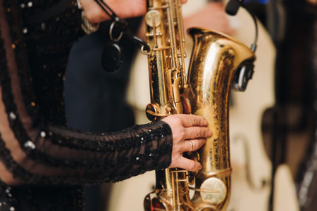 Concert view of female saxophonist musician, saxophone sax player woman with vocalist and musical band during jazz orchestra show, performing music on a scene in the stage lights in a musical clubの写真素材